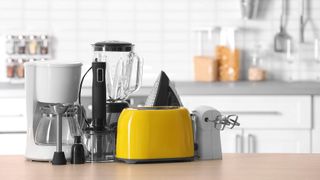 Kitchen appliances on a kitchen counter including a blender, coffee maker, toaster and immersion blender