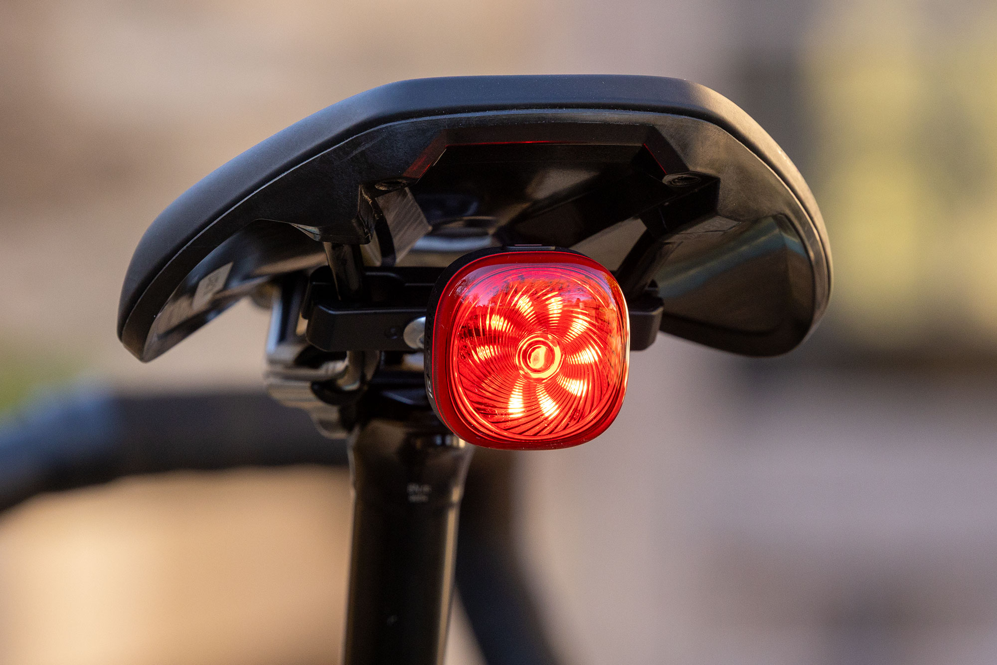 The square-shaped IGPSport TL50 smart rear bike light, with its fun spiralling LED design, mounted to the saddle rails of a Specialized Turbo Creo