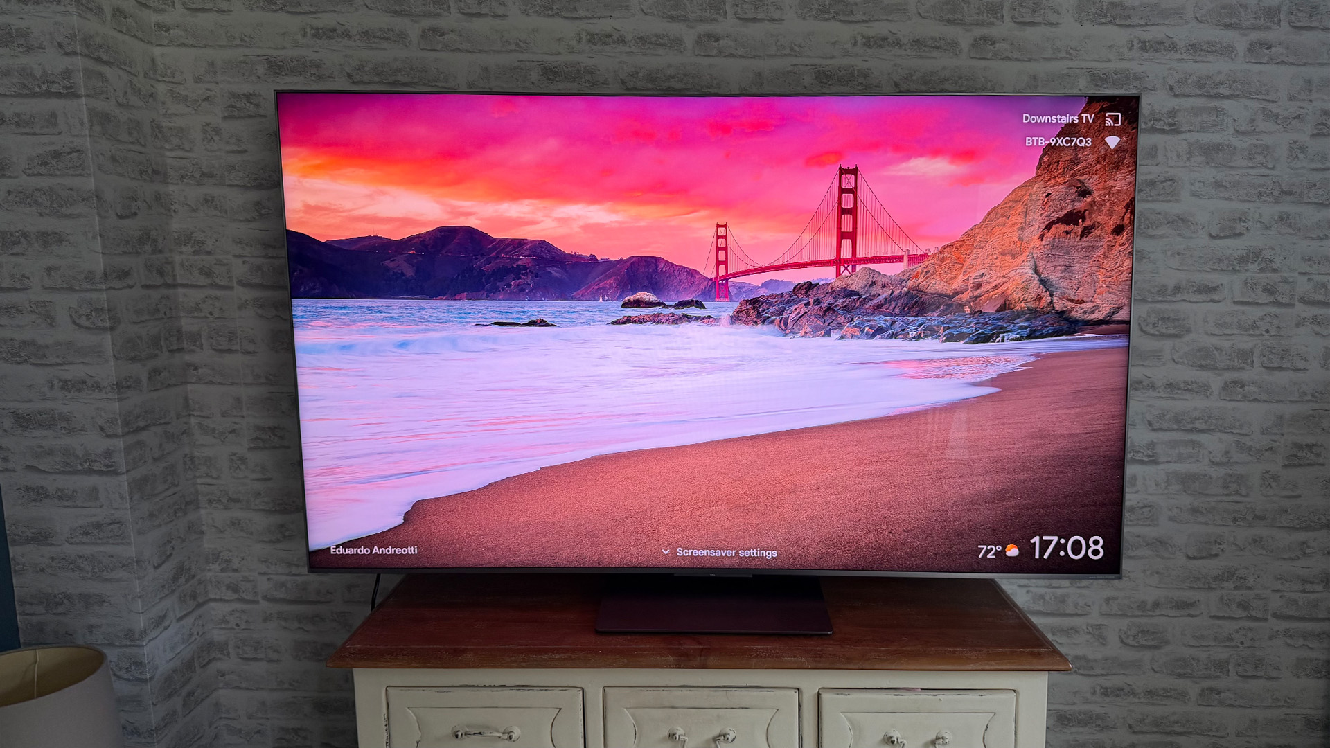 TCL C8L Mini LED TV in front of brick wall on screen is Golden Gate bridge