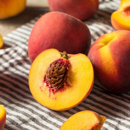 Cut peach with exposed pit on a striped towel