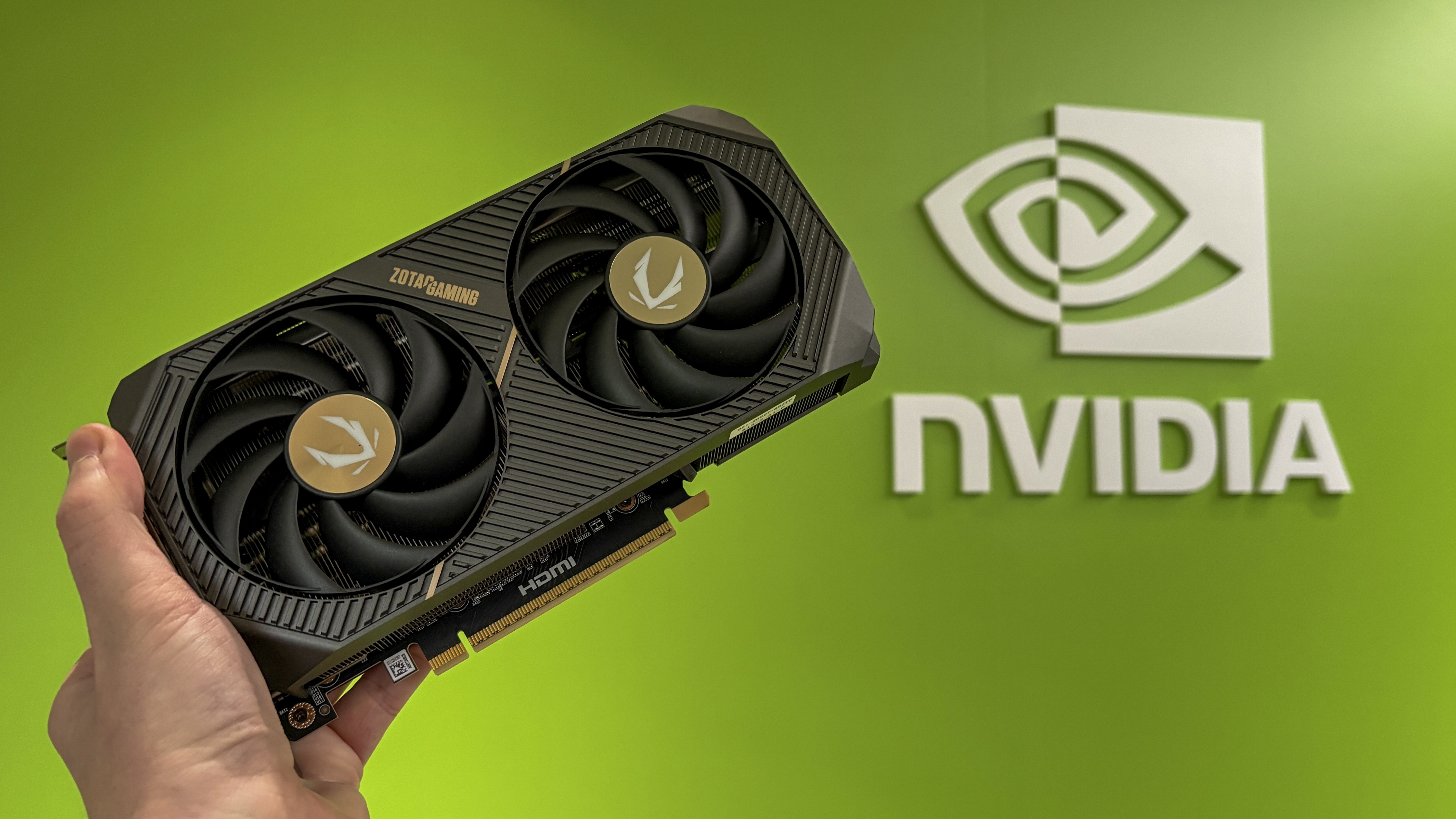 Nvidia RTX 50-series GPU held in hand with Nvidia logo on green background