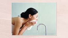 Image of a side view of a woman washing her face with a flannel in front of a running tap, set in a white frame against a pink watercolour-style background