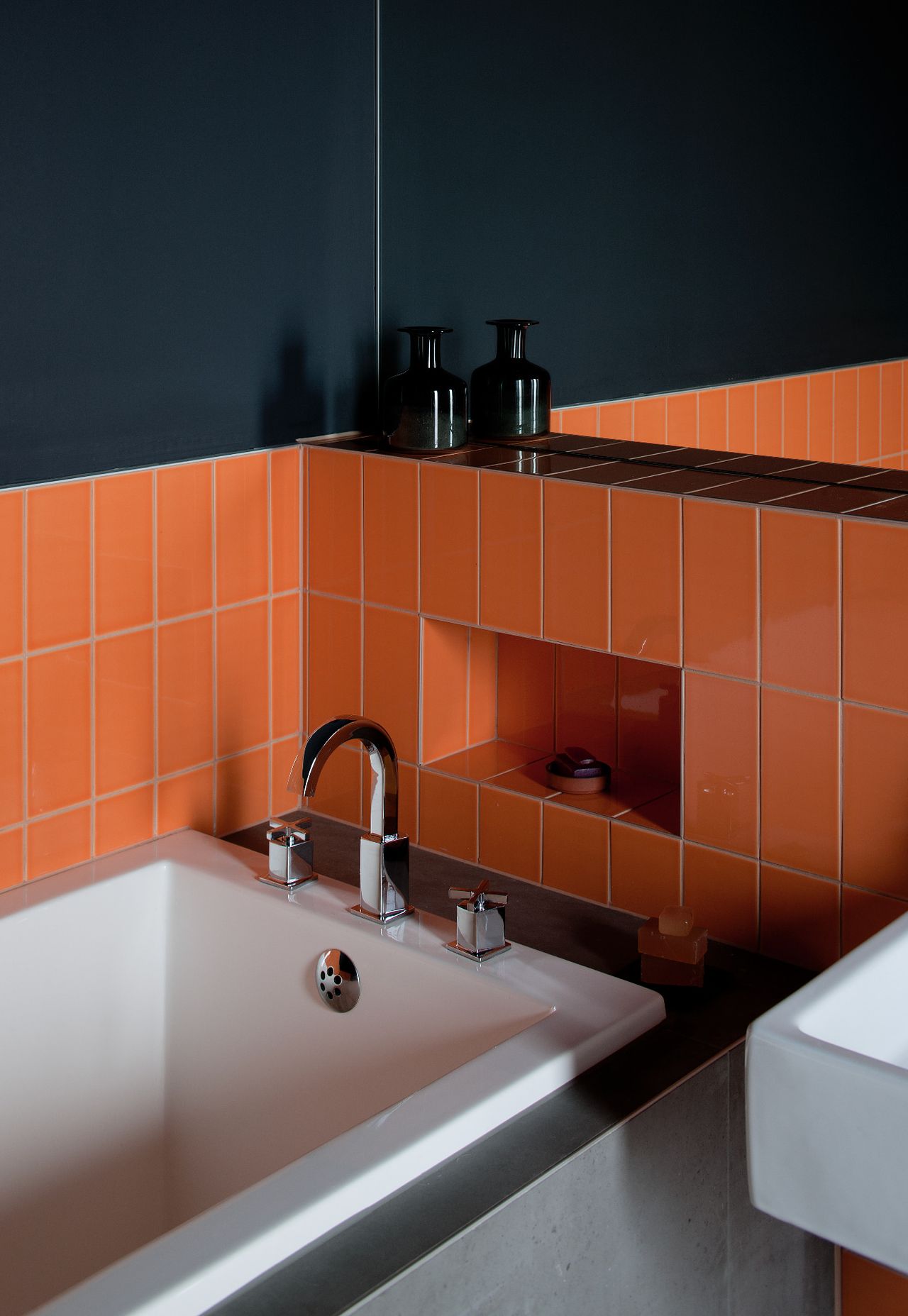 A bathroom with orange tiles and black walls