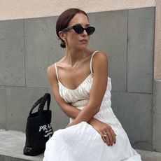 Debora Rosa wearing a white sundress with cateye sunglasses and white net flats.