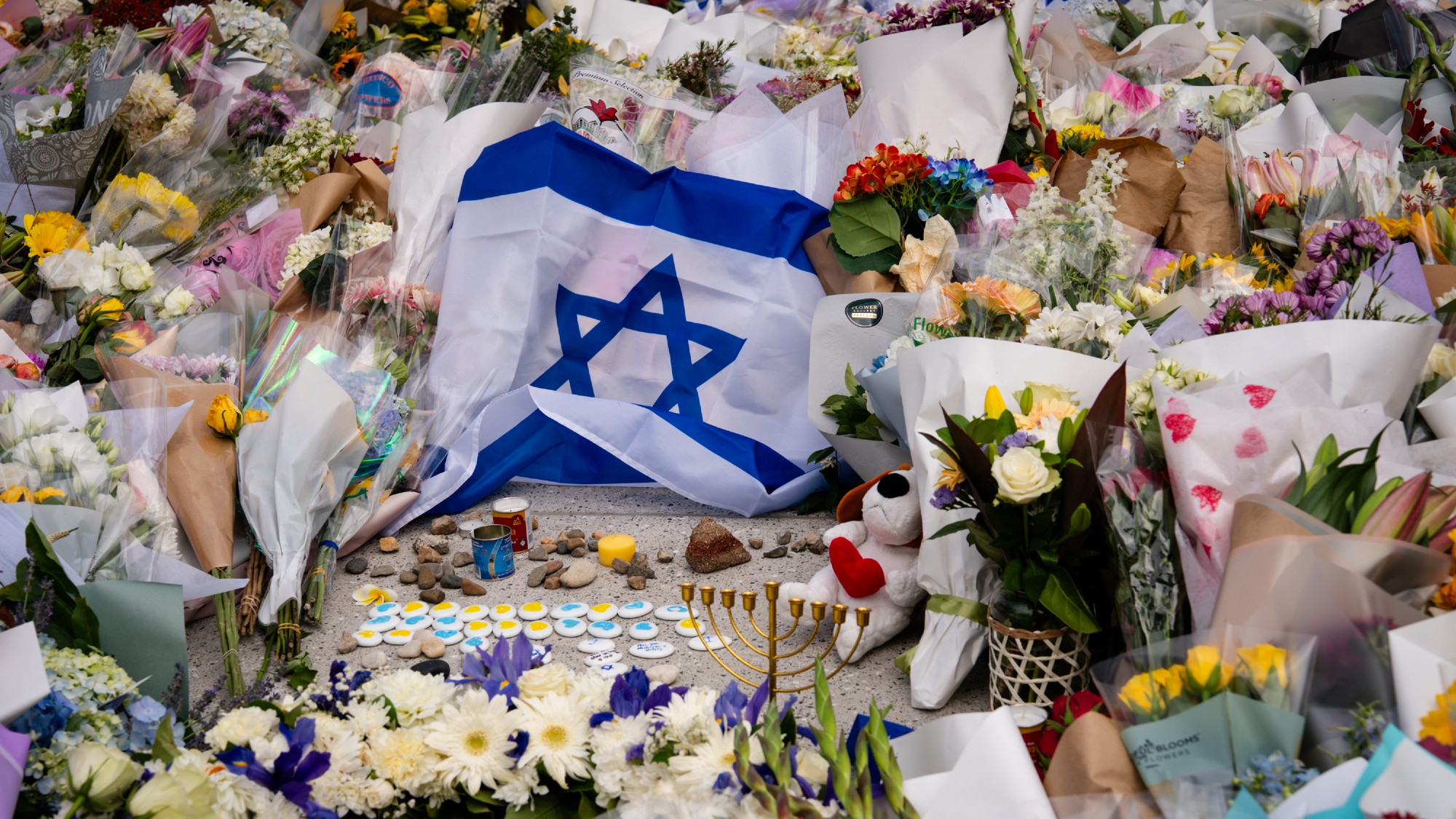 An Israeli flag and flowers in a tribute display