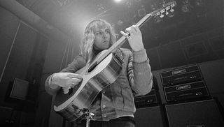 Alex Lifeson plays an acoustic guitar in the studio