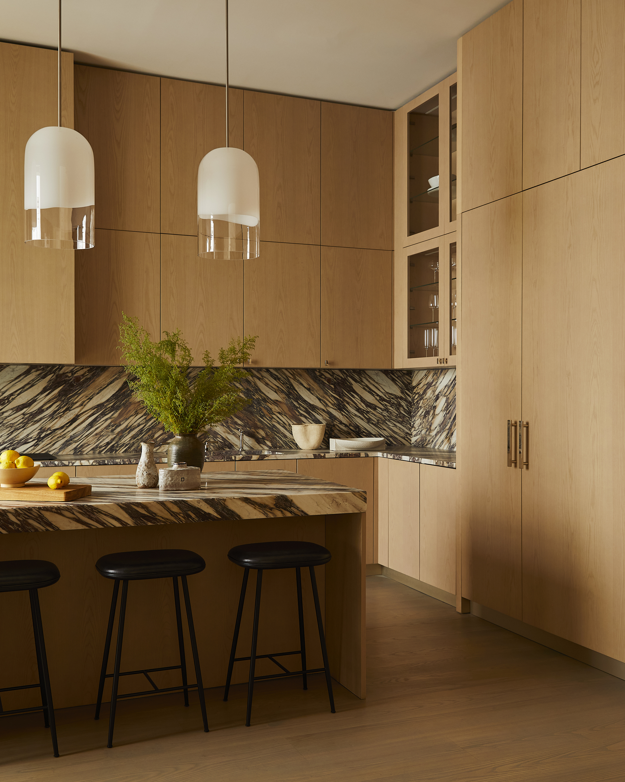 oak timber kitchen with marble backsplash and matching kitchen island, with black barstools and pendant lights hanging overhead