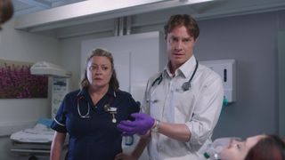 Embargoed 11/02/25 Laurie Brett and Max Brown as midwife Maria and consultant Henry preparing to treat a patient.