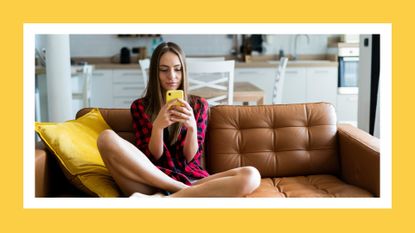 woman on phone while sitting on couch in her apartment, meant to symbolize someone on an online dating app for dating sunday 2023