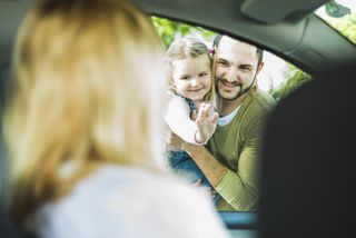 Girl with father saying goodbye to leaving mother in car