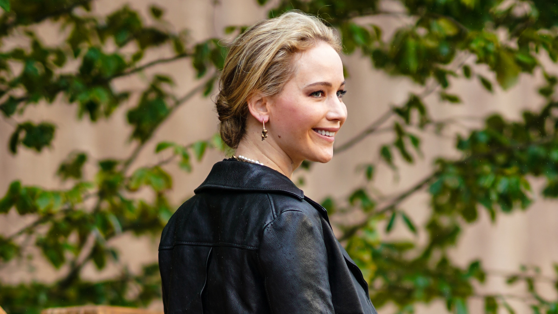 Jennifer Lawrence on a red carpet wearing a leather jacket and jeans