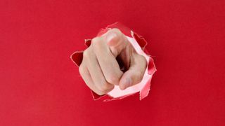Finger pointint through red background. 
