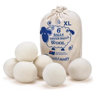 A white drawstring bag of wool dryer balls with a blue symbol next to six wool dryer walls