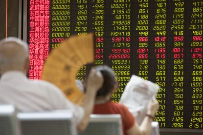 Investors look at a screen projecting Chinese stocks.