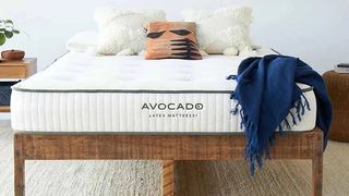 Saatva vs Avocado: The Avocado Latex Mattress on a dark wooden bed frame and dressed with a navy throw
