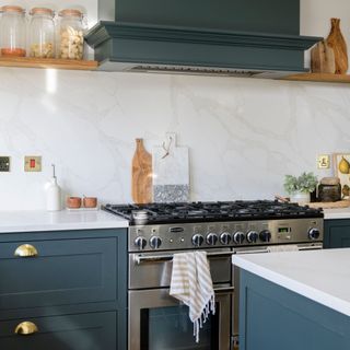 White kitchen with blue cabinets, a large silver oven and marble backsplash