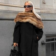 @clarabergertorres wearing a black coat, brown faux-fur scarf, sunglasses, leather tote and gold earrings 