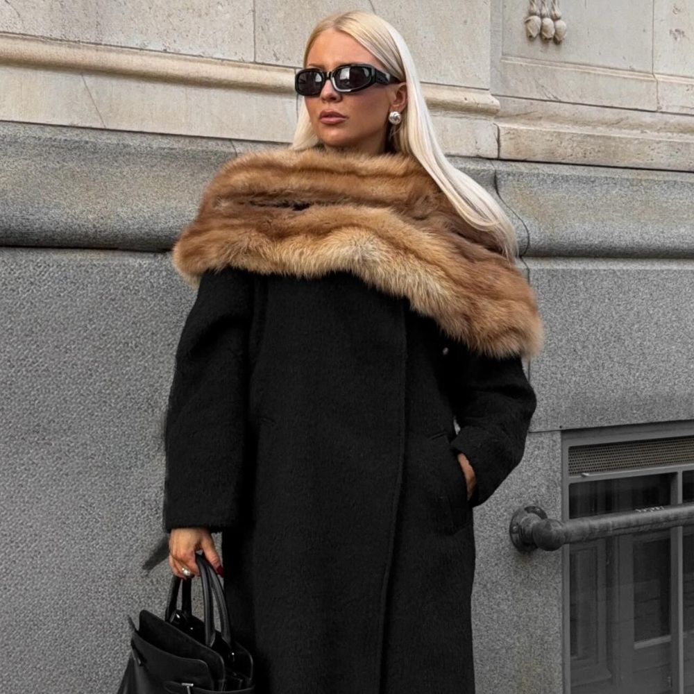 @clarabergertorres wearing a black coat, brown faux-fur scarf, sunglasses, leather tote and gold earrings 