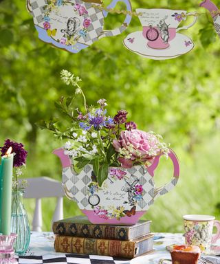 Alice In Wonderland themed table decor shaped like teap pot and tea cups filled with flowers