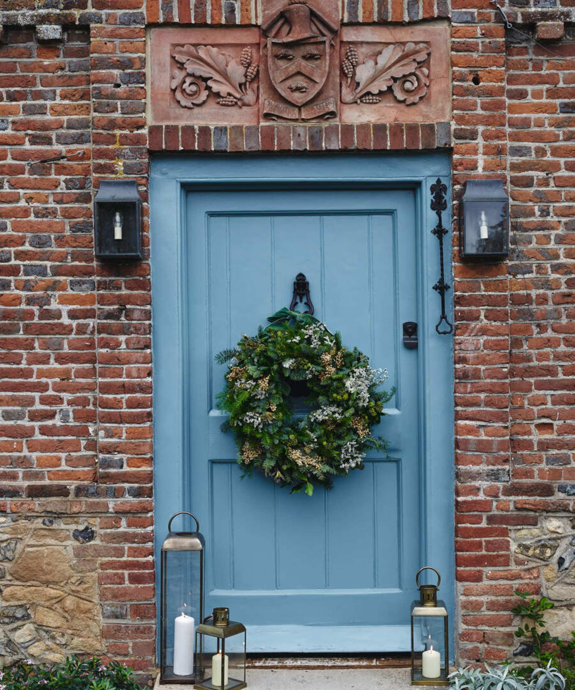 a brick house with a blue front door with a wreath hanging from it