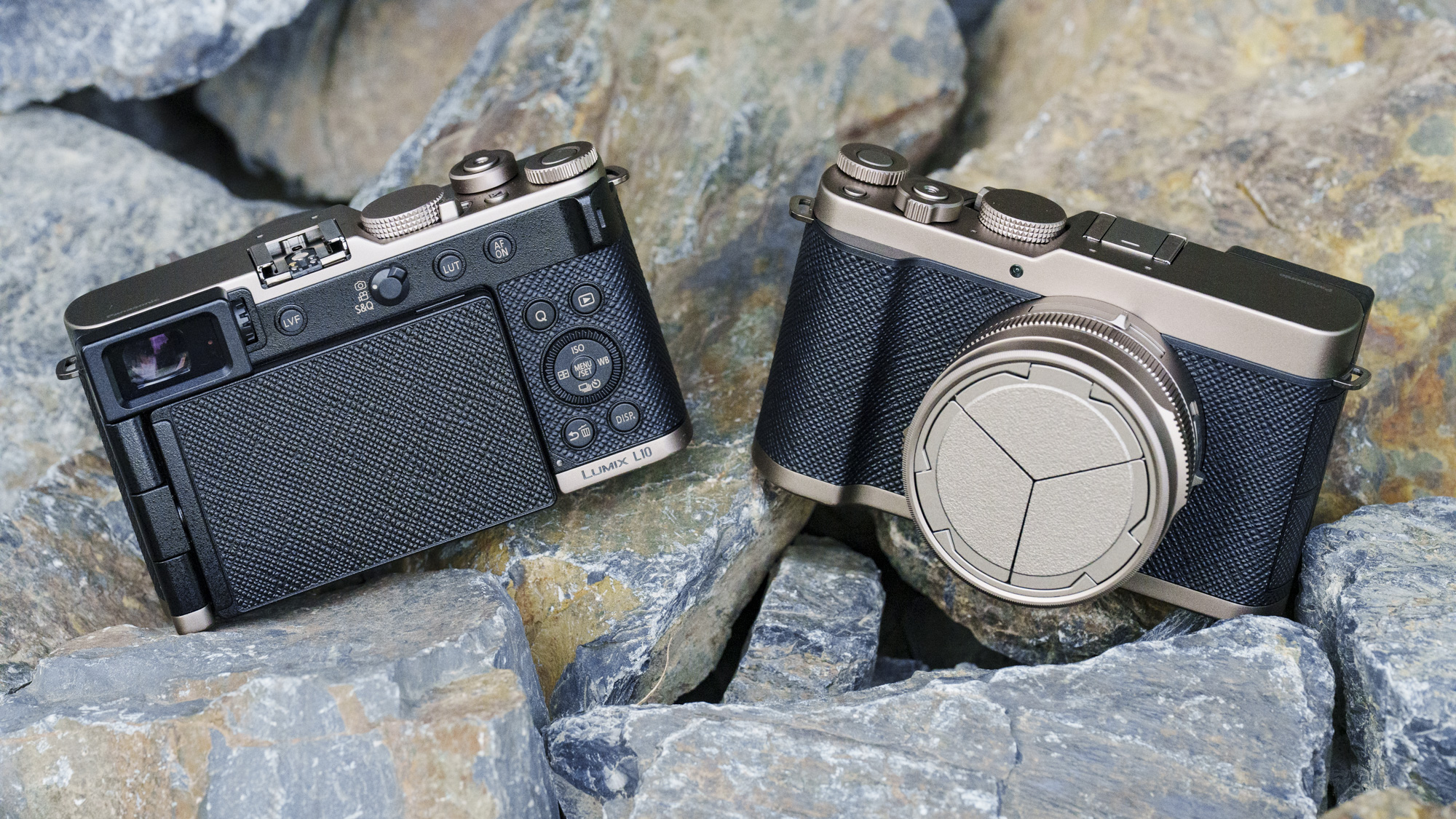 The Gold Titanium Special Edition of the Panasonic Lumix L10 compact camera, sat on gray and rust-colored rocks