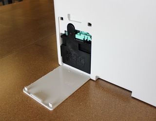 A waste toner bin is located on the side of the Samsung ProXpress C3060W, which collects the excess toner powder that accumulates after using this wireless laser printer.