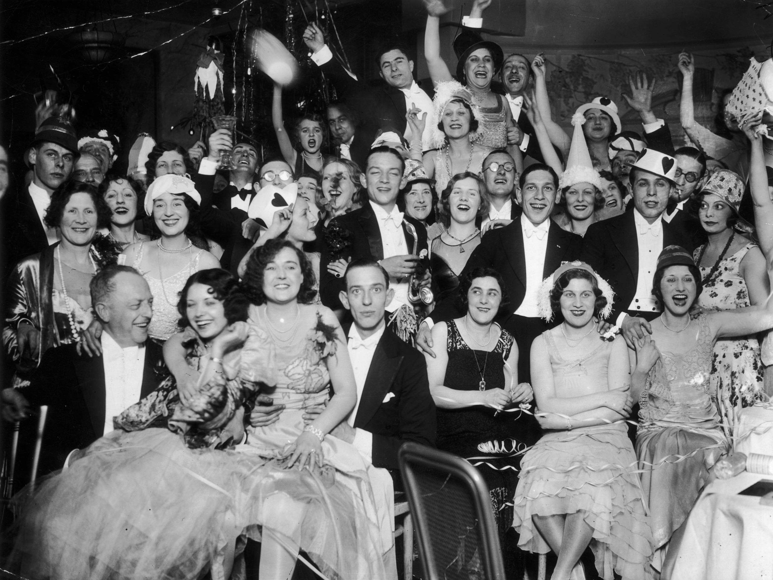 A group of men and women, in fine dining clothes, celebrate new years eve in 1930