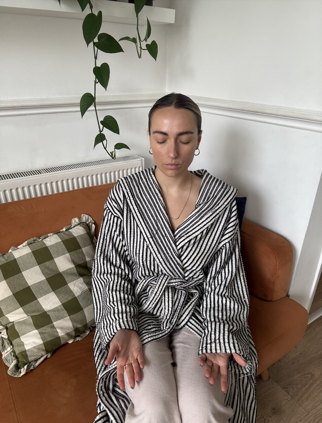 Woman wears striped dressing gown and meditates