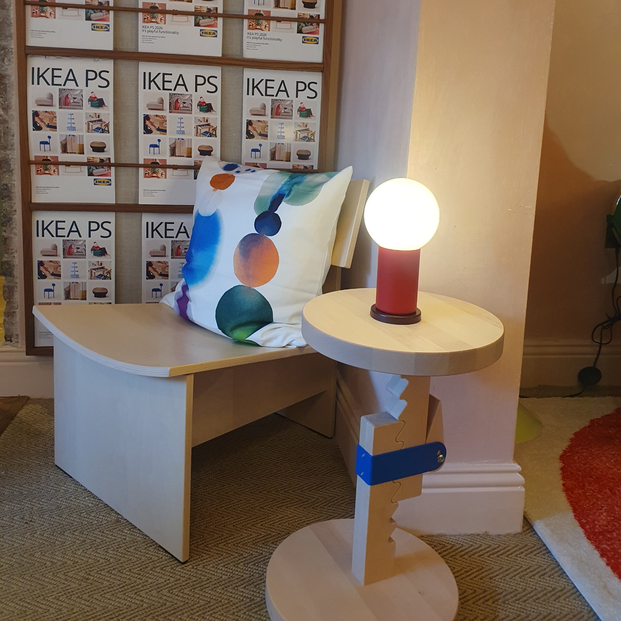 The IKEA PS 2026 easy chair with a cushion on top and the height-adjustable stool used as a side table with a portable light on top