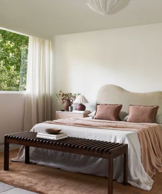 small neutral bedroom designed with a textured wavy headboard and rose pink accents