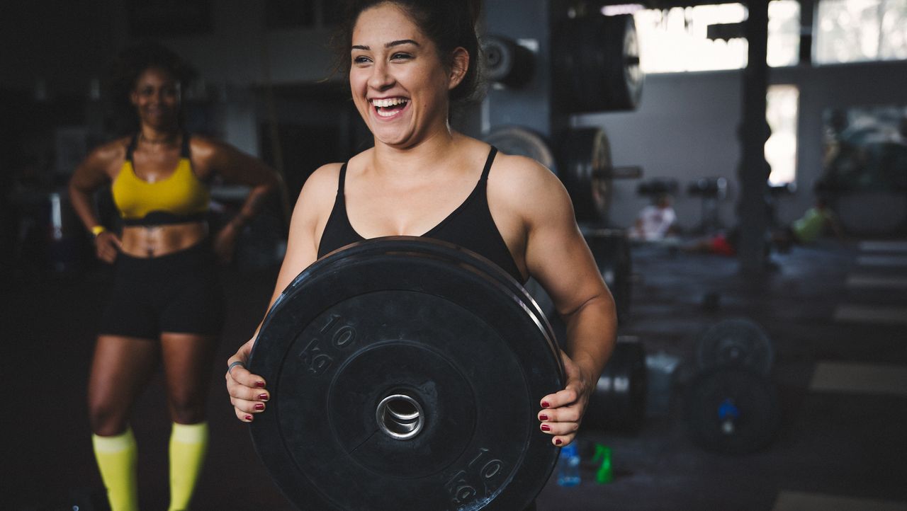 Woman carrying weight plate in gym