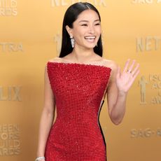 Anna Sawai arriving at the 2025 SAG Awards weraing a red beaded dress and diamond earrings