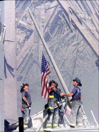 firemen raise an american flag at the world trade center