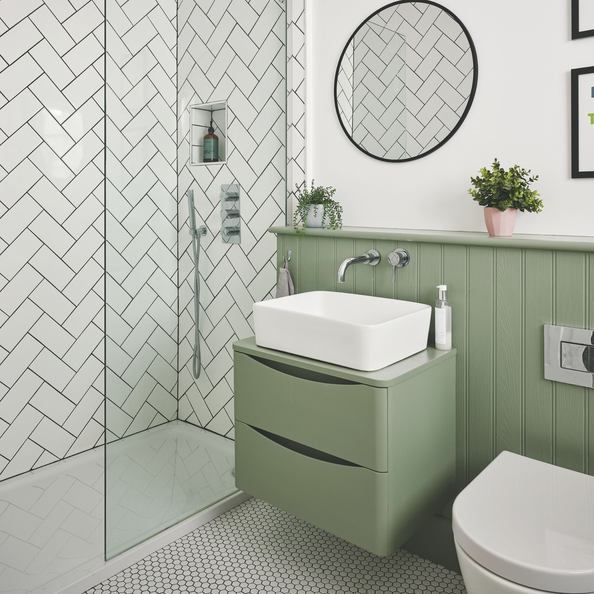 White painted bathroom with green panelling at the bottom with a matching green sink vanity, and a shower area