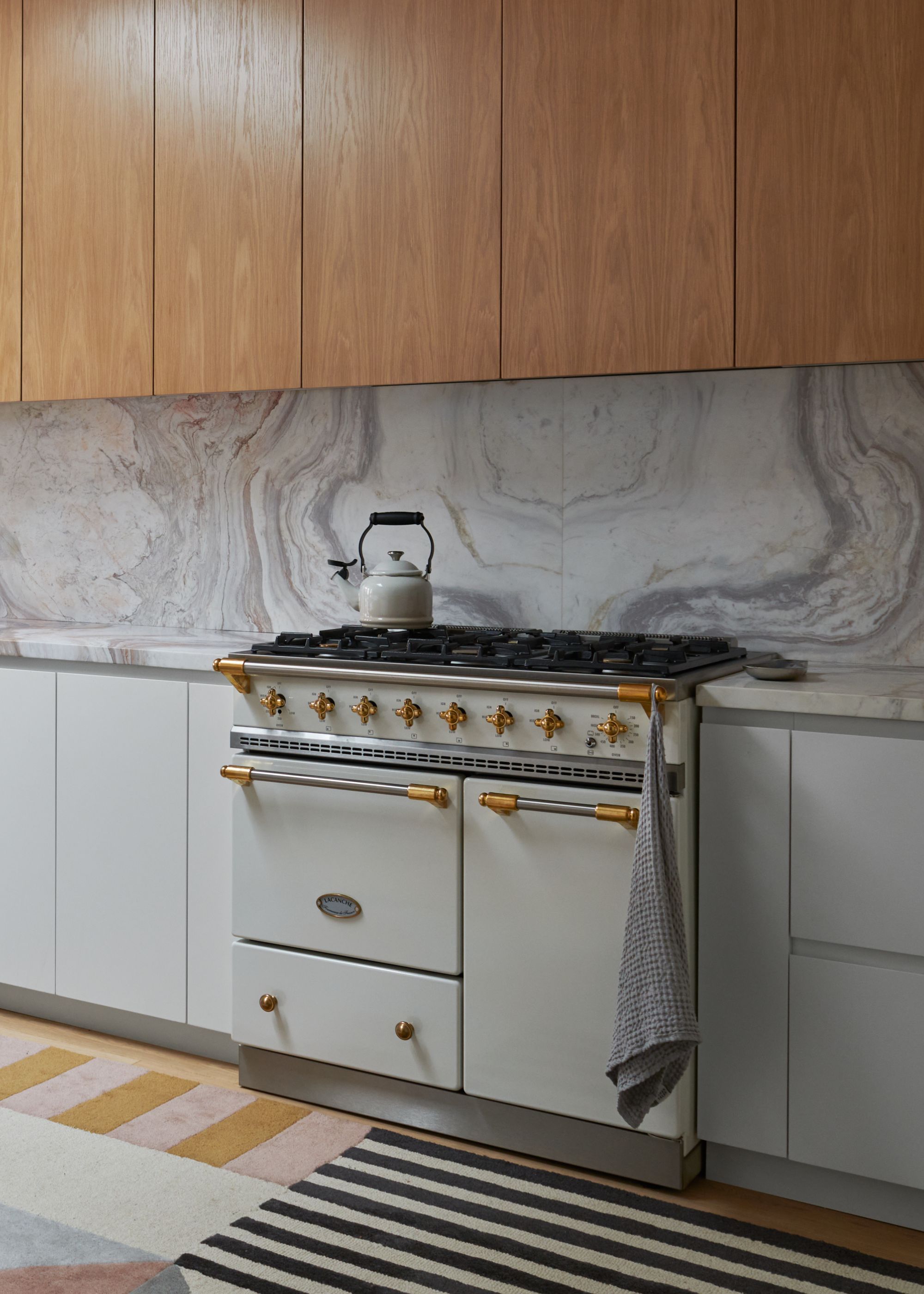 A white AGA gas oven in a home with a gas top and a kettle pot on top of it. There is also a kitchen towel hanging on the side