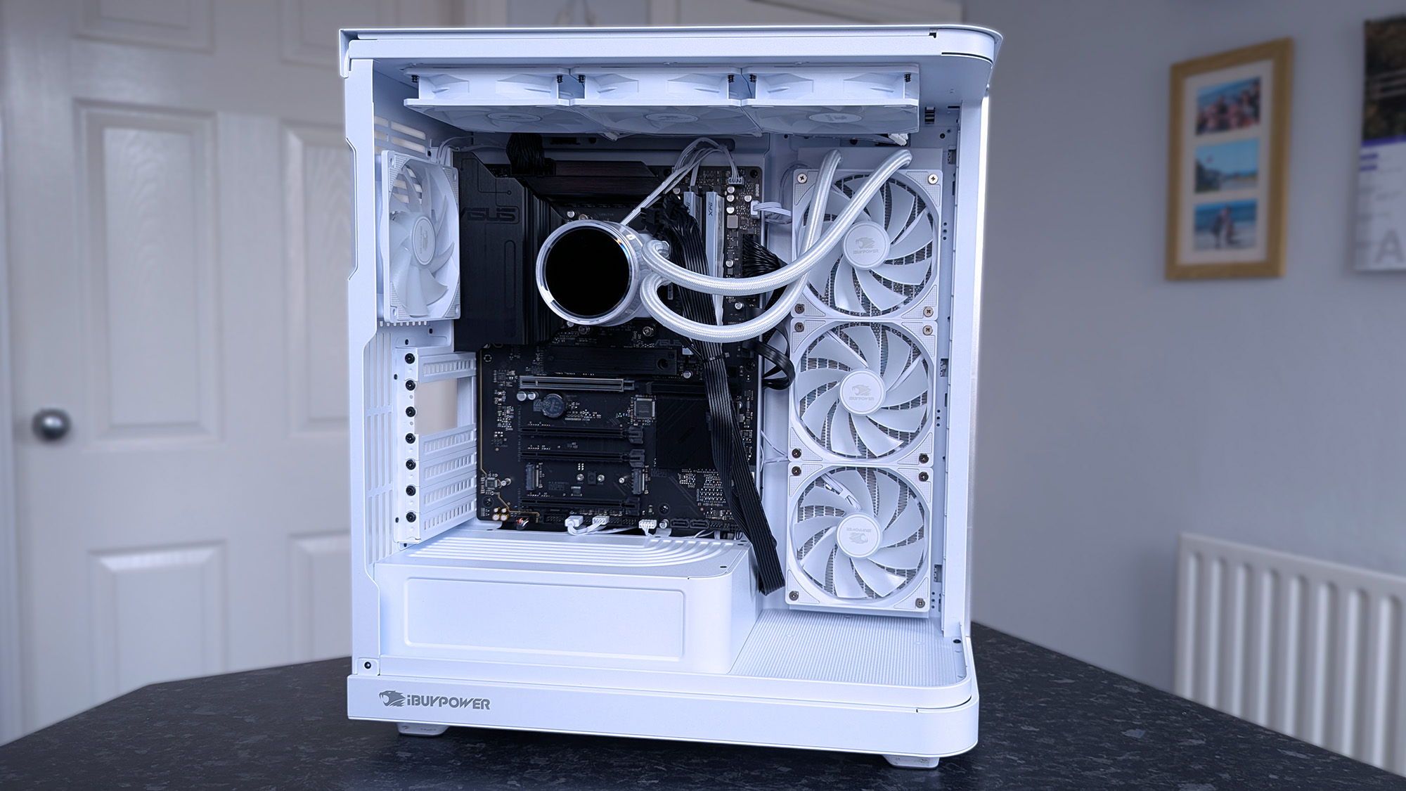 A sleek white iBUYPOWER RDY Trace X R01 computer with visible cooling fans and a liquid cooling system on the inside. It's on a dark surface.