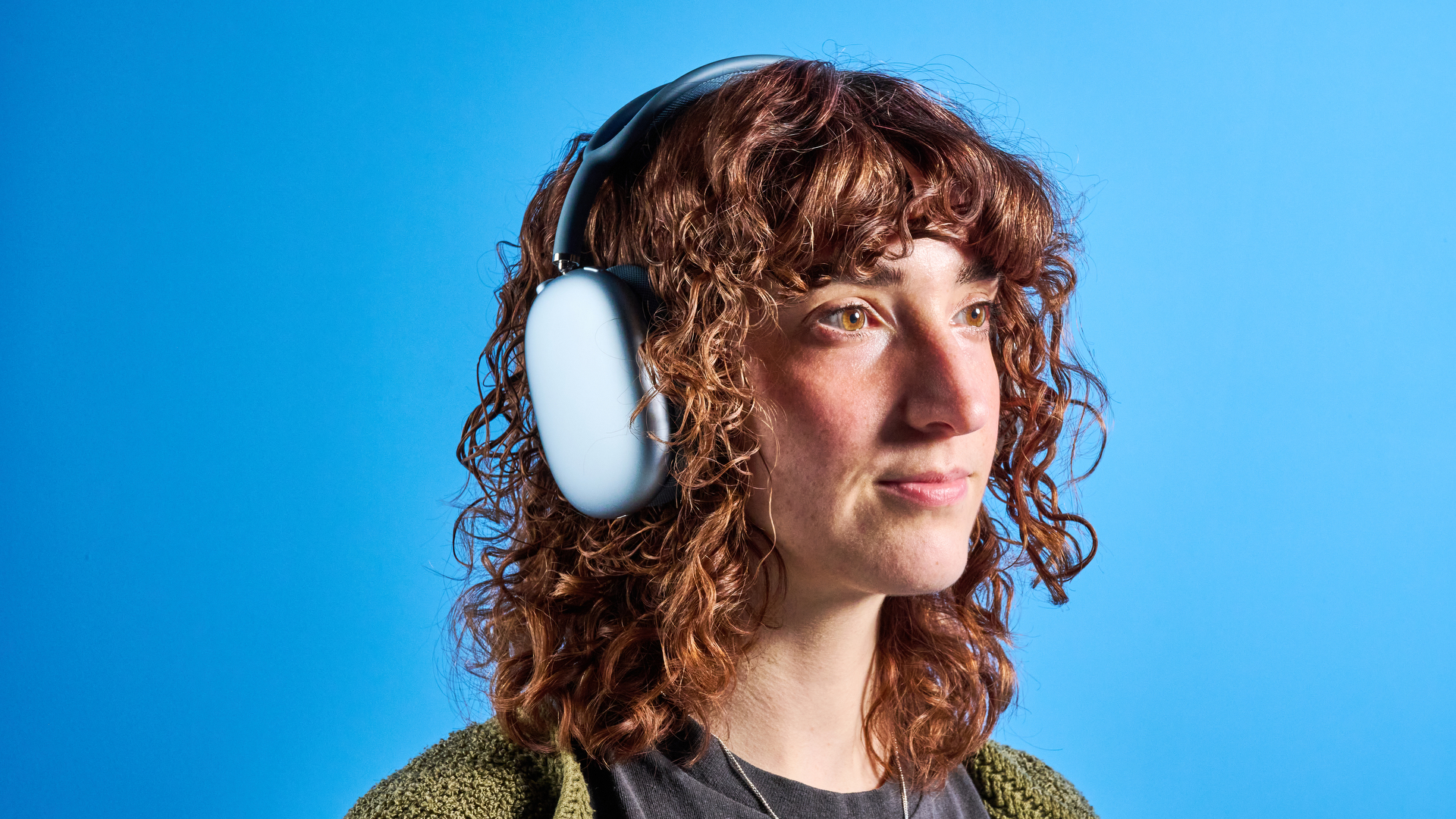 the apple airpods max 2 in blue photographed against a blue tom's guide background, showing the mesh headband, anodized aluminum ear cups, carry case, and controls