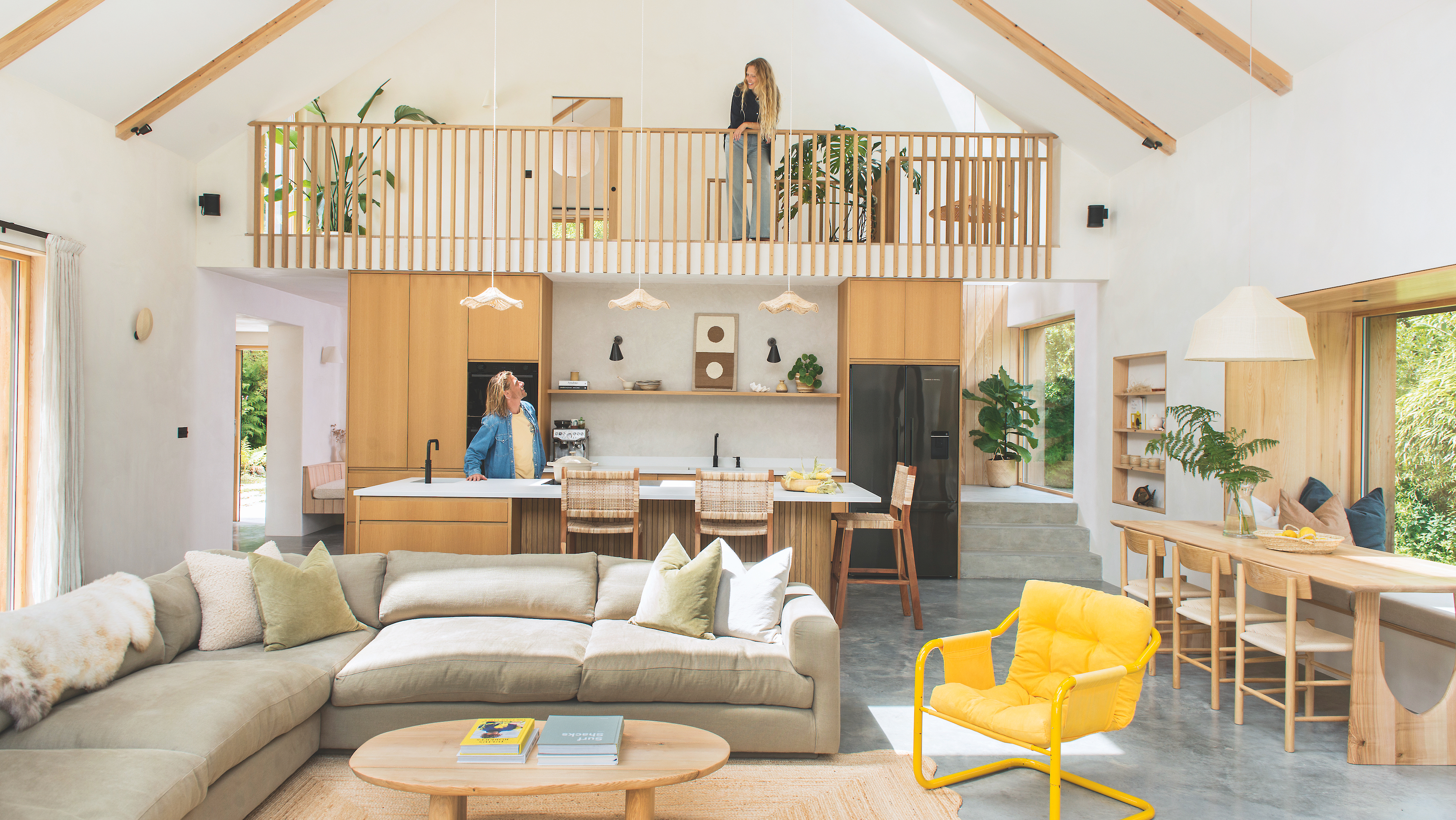 interior of self-build coastal house in cornwall featuring an open-plan living space with a kitchen, dining and seating area, and a mezzanine above