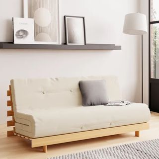A cream upholstered wooden futon sofa bed in a cream living room