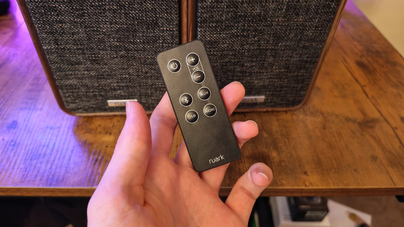 A reviewer holding the remote for the Ruark MR1 MK3 Speakers