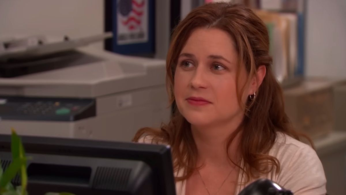 Pam Beesly looking satisfied by her desk in The Office.