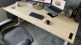 A side shot of the Sway standing desk, with chair, laptop and other desk accessories.