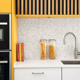 granite kitchen splashback, white surfaces with jars of pasta and sink