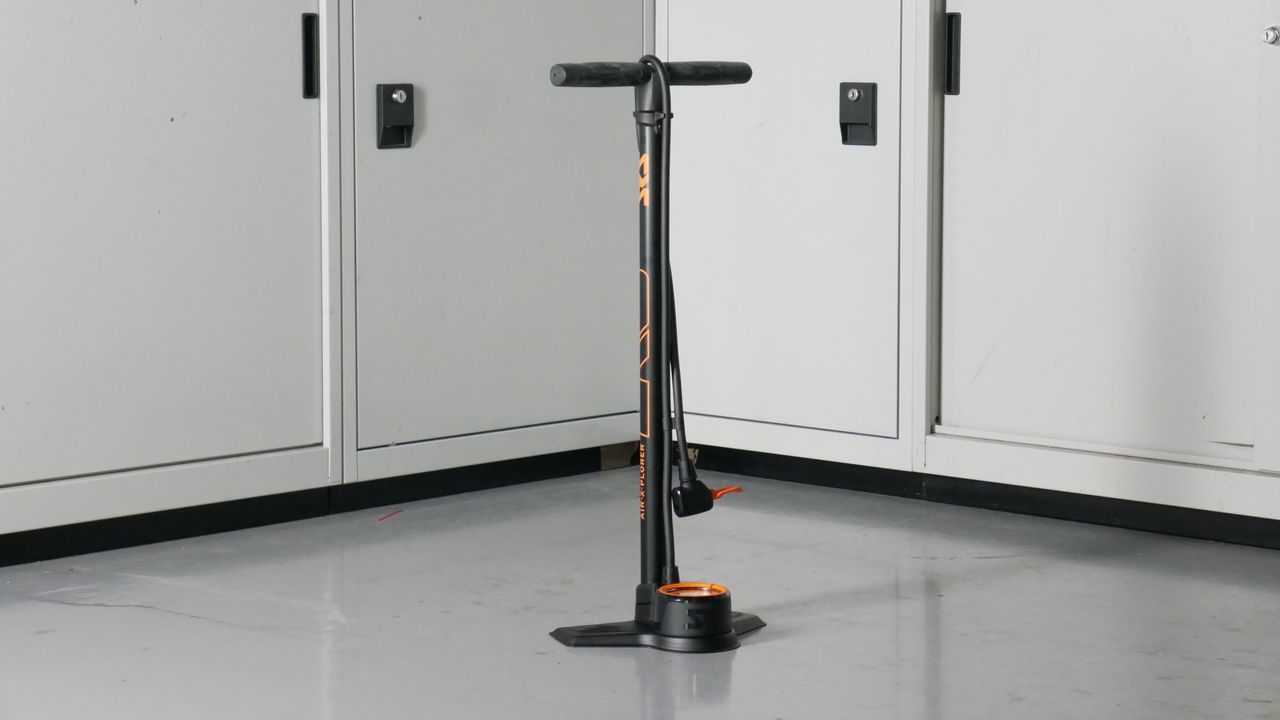 SKS Air-X-Plorer bike track pump in black and orange set against a background of some workshop cabinets
