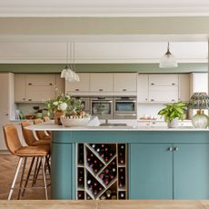 Green coloured open-plan kitchen-diner with peninsula