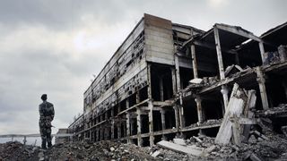 Soldier in military uniform stands on the ruins.