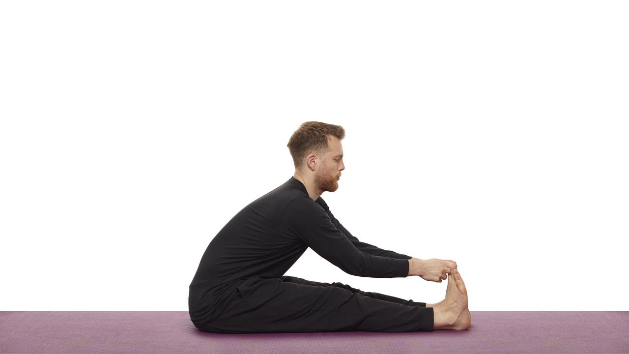 Yoga teacher Nick Higgins performs seated forward bend