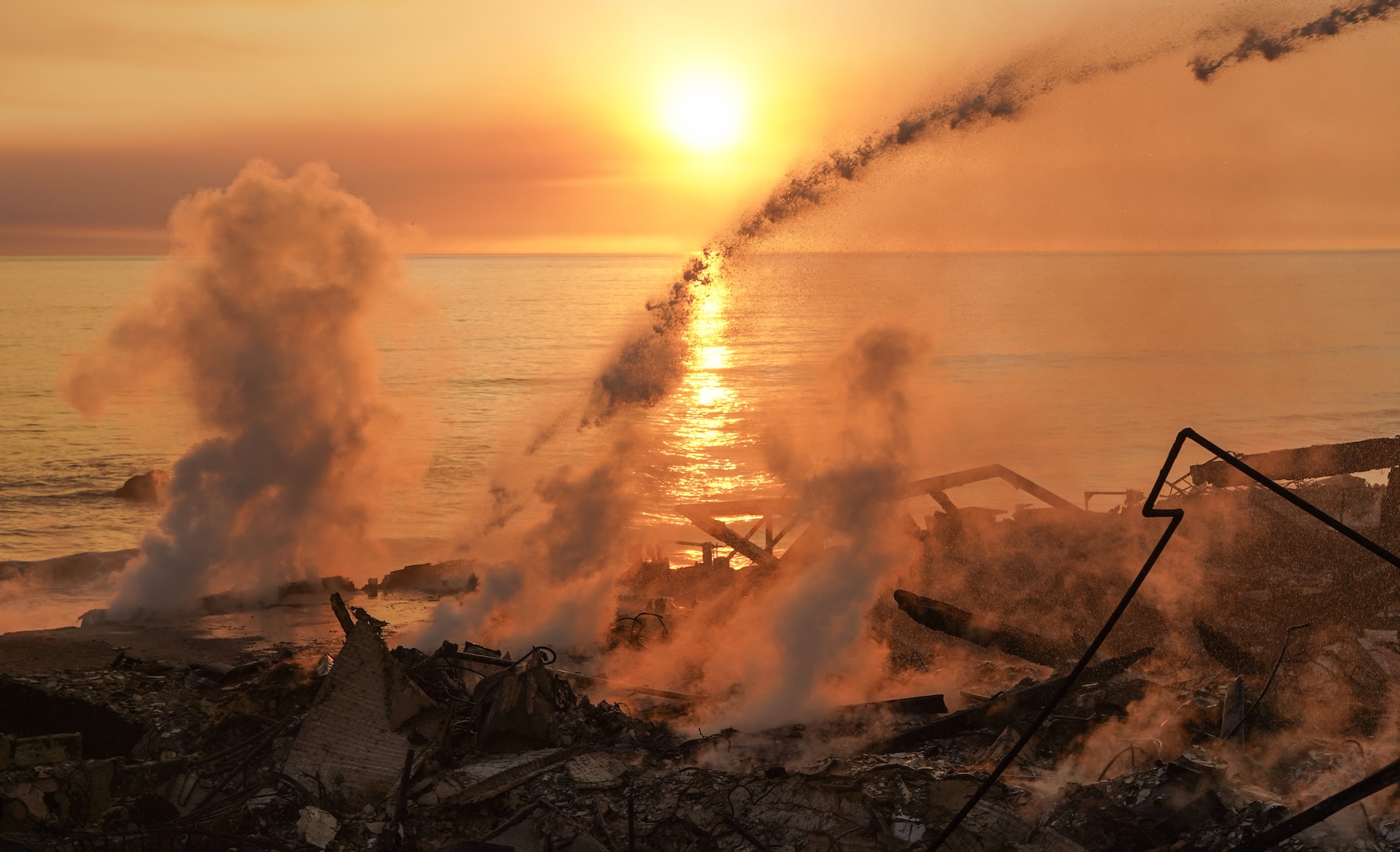 a view of burning debris on a beach at sunset