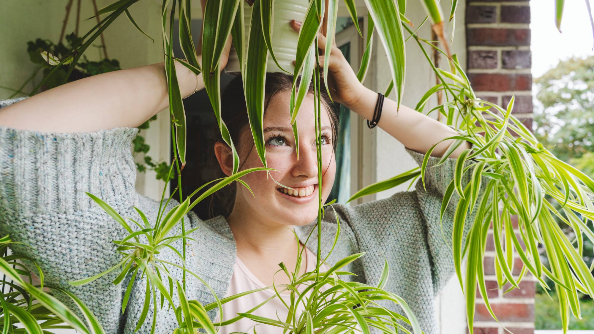 Girl holds spider plant above her head smiling