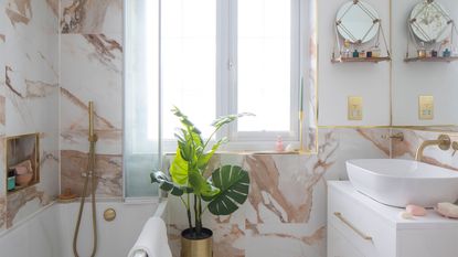 marble and white bathroom with bath and gold shower